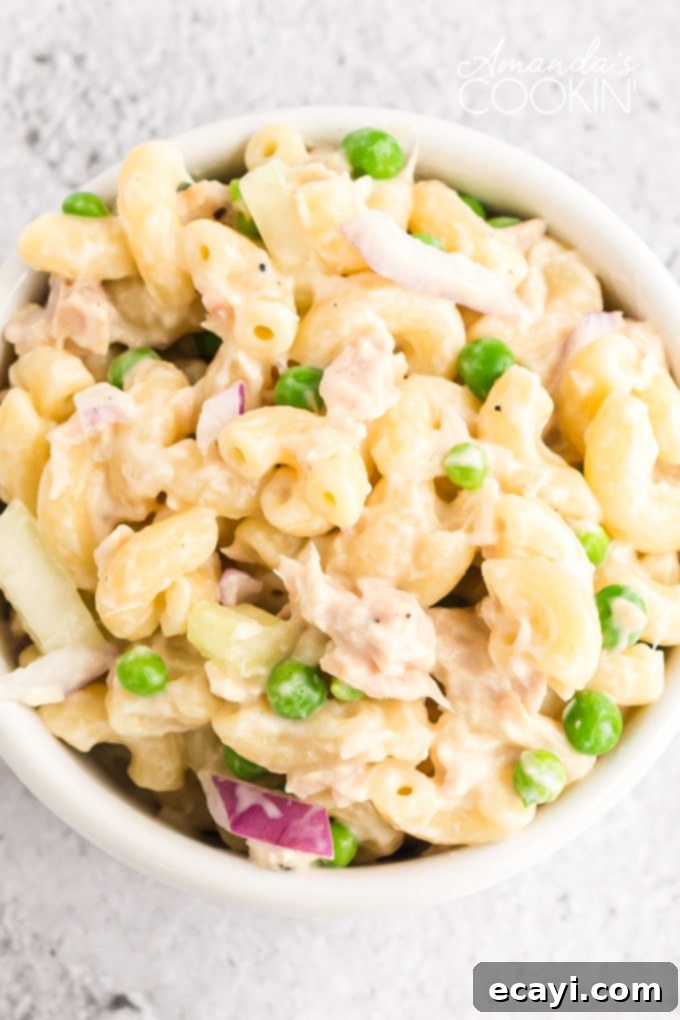 This recipe for tuna pasta salad is easy to make and is perfect for potlucks and barbecues, or just a protein packed lunch! close up of tuna pasta salad with a fork in it, highlighting the creamy texture and fresh ingredients