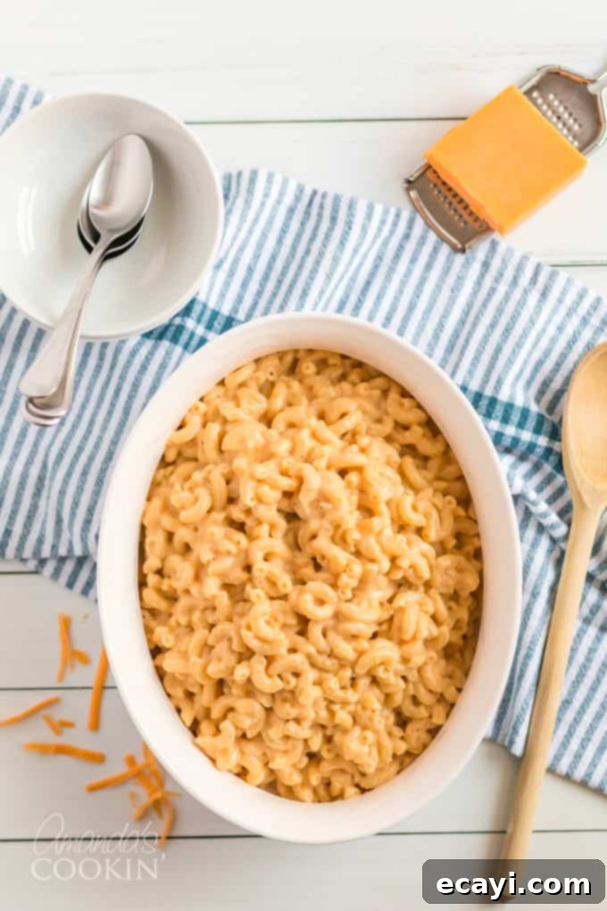 My stovetop mac and cheese recipe is easy to make, uses a homemade cheese sauce, and is perfectly creamy. Make this mac and cheese today! #macaroni #macandcheese #cheese #sides #dinnersides #lunch #pasta A large bowl of golden, creamy stovetop mac and cheese, perfectly garnished and ready to serve.