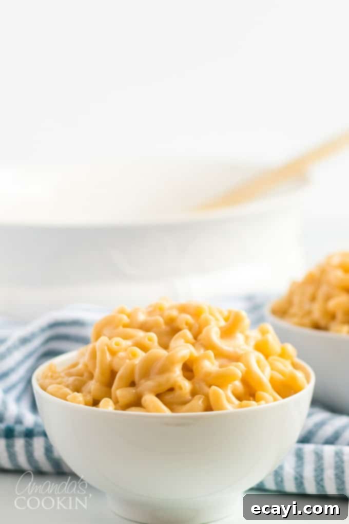 My stovetop mac and cheese recipe is easy to make, uses a homemade cheese sauce, and is perfectly creamy. Make this mac and cheese today! #macaroni #macandcheese #cheese #sides #dinnersides #lunch #pasta A close-up shot of a bowl of freshly made stovetop mac and cheese, steaming hot and ready to be eaten.