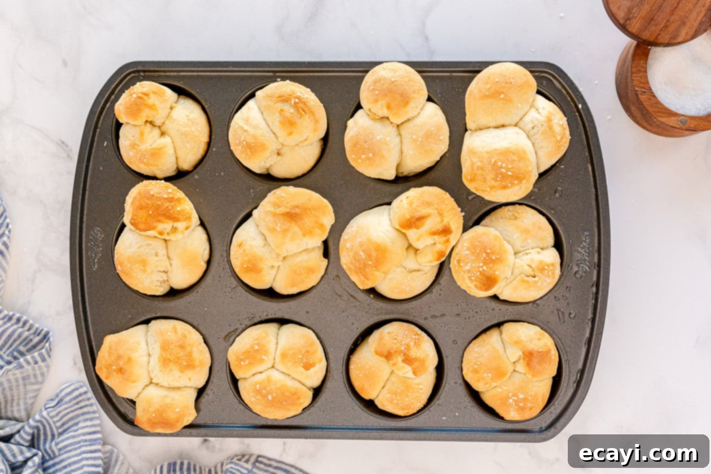 Irresistible Tear-and-Share Dinner Buns 11 Freshly baked golden brown dinner rolls in a muffin pan, just out of the oven.