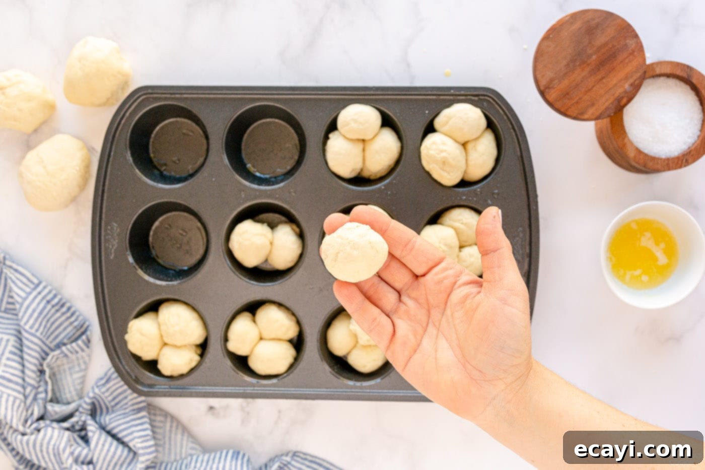 Irresistible Tear-and-Share Dinner Buns 9 Small balls of dough arranged in a muffin pan, ready for butter and salt.