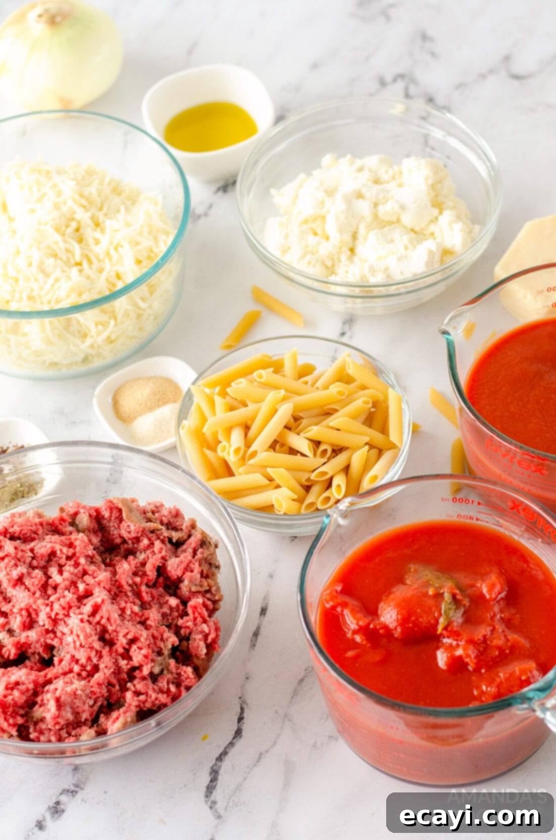Ultimate Cheesy Ziti Bake 4 A selection of fresh ingredients laid out, including onions, ground beef, spices, tomato products, and various cheeses, ready for baked ziti preparation