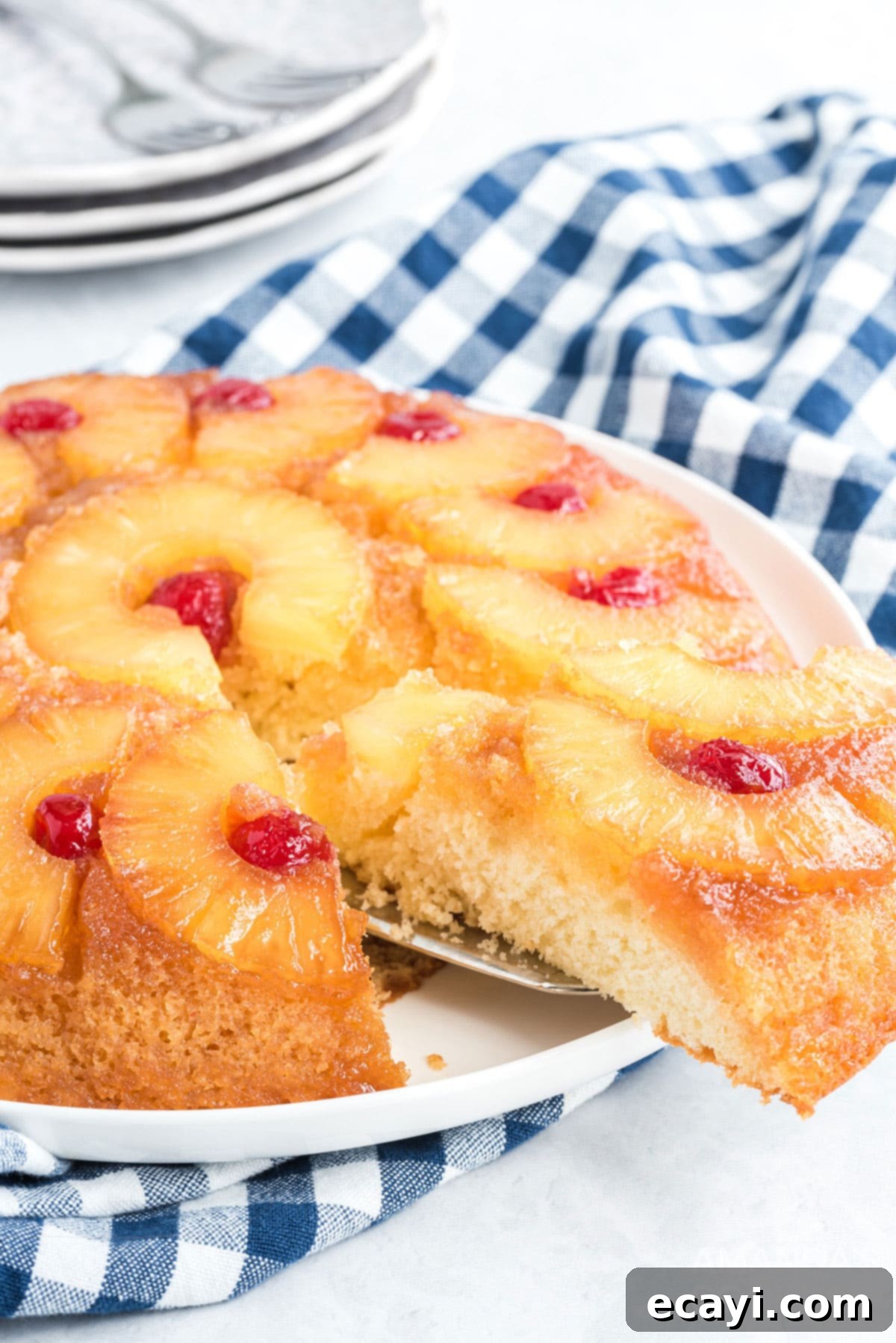 There's nothing quite like a pineapple upside down cake that's been baked to caramely perfection in a seasoned cast iron skillet! removing a slice of pineapple upside down cake from the main cake with a spatula