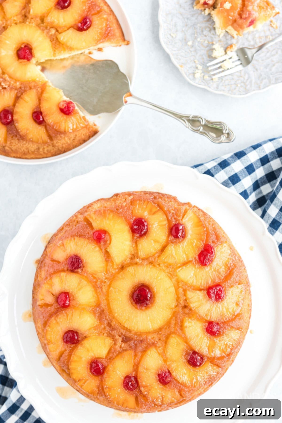 There's nothing quite like a pineapple upside down cake that's been baked to caramely perfection in a seasoned cast iron skillet! overhead view of two pineapple upside down cakes, one whole and one with a slice removed, both in cast iron skillets