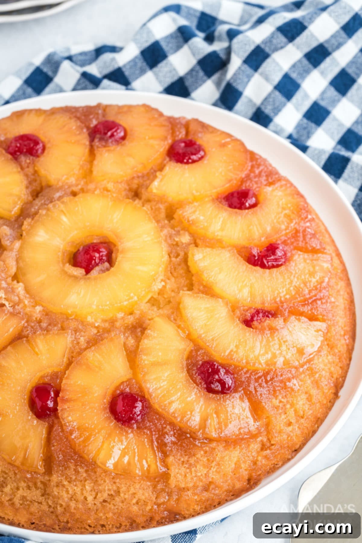 There's nothing quite like a pineapple upside down cake that's been baked to caramely perfection in a seasoned cast iron skillet! close up of a slice of pineapple upside down cake, highlighting the caramel topping, pineapple ring, and maraschino cherry