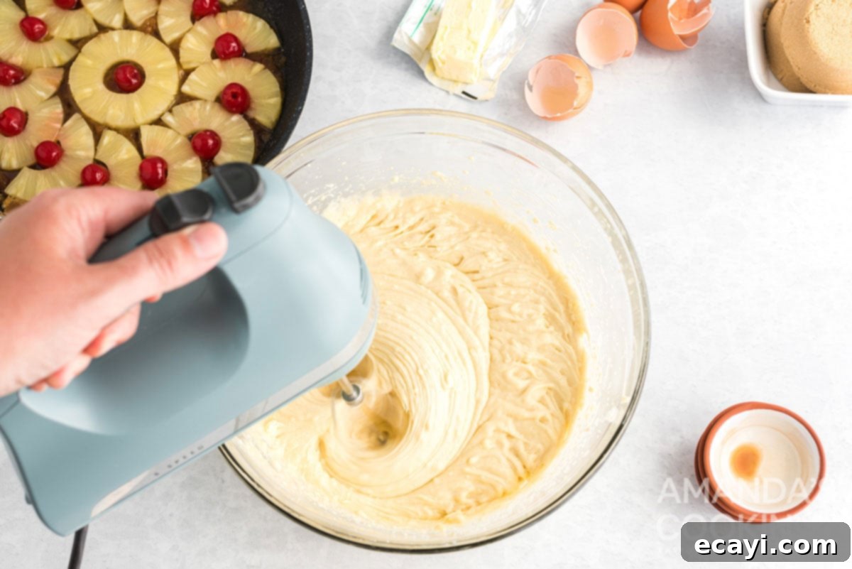 Golden Skillet Pineapple Flip 7 mixing cake batter with an electric hand mixer