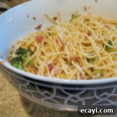 Spaghetti with Pancetta and Broccoli 2 A close up photo of spaghetti with pancetta and broccoli in a bowl, garnished with herbs.