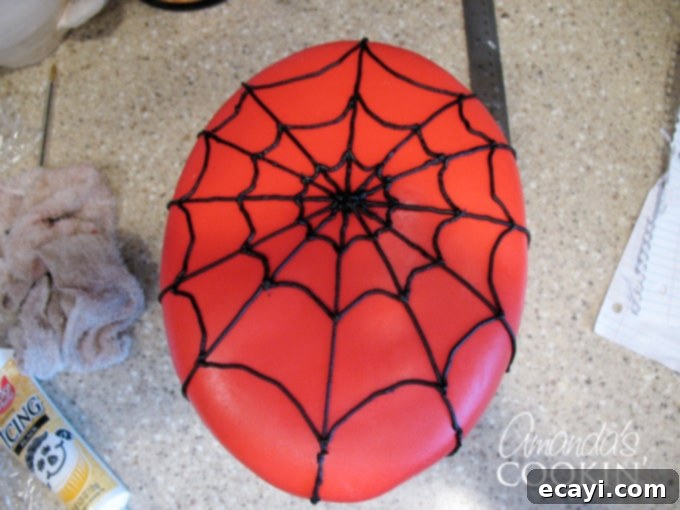 Spiderman Cake Magic: Homemade Marshmallow Fondant 7 A photo of a Spiderman cake with its red fondant base and meticulously piped black web details.