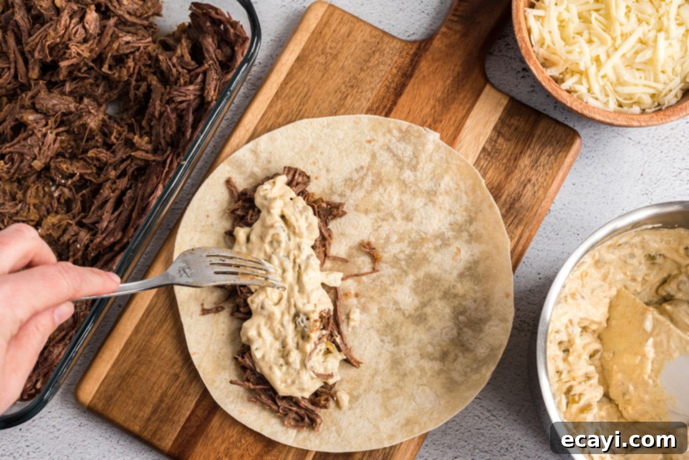 Classic Smothered Beef Enchiladas 16 Adding creamy sour cream mixture to shredded beef enchiladas