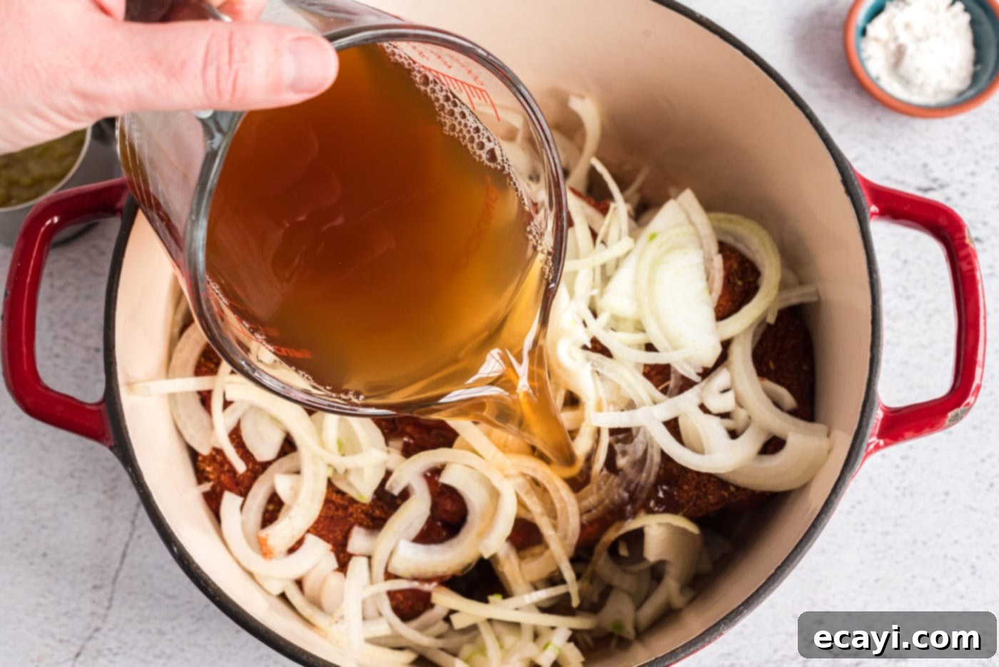 Classic Smothered Beef Enchiladas 7 Pouring beef broth and vinegar into dutch oven with onions and chuck roast