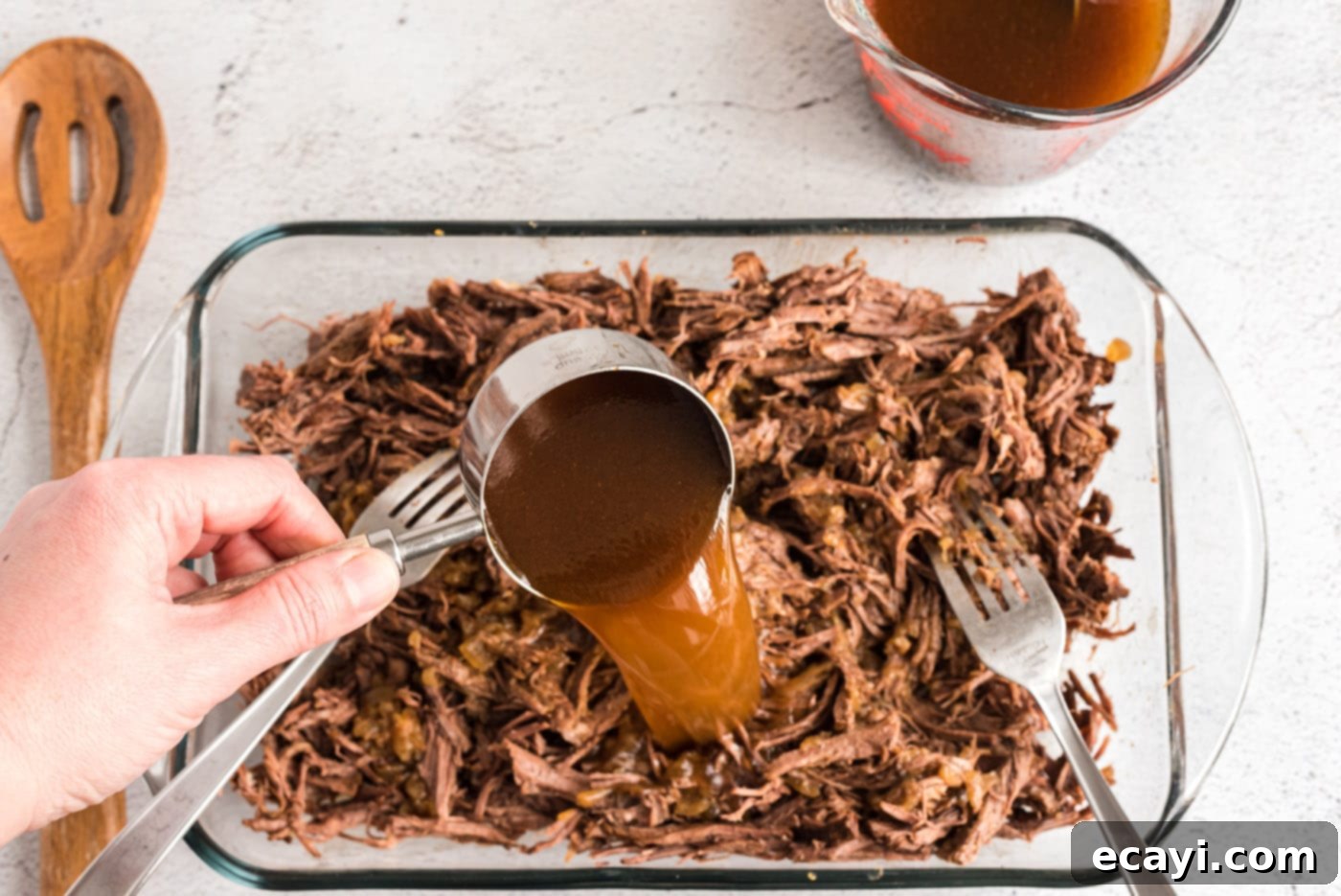 Classic Smothered Beef Enchiladas 10 Pouring pan juices into shredded chuck roast