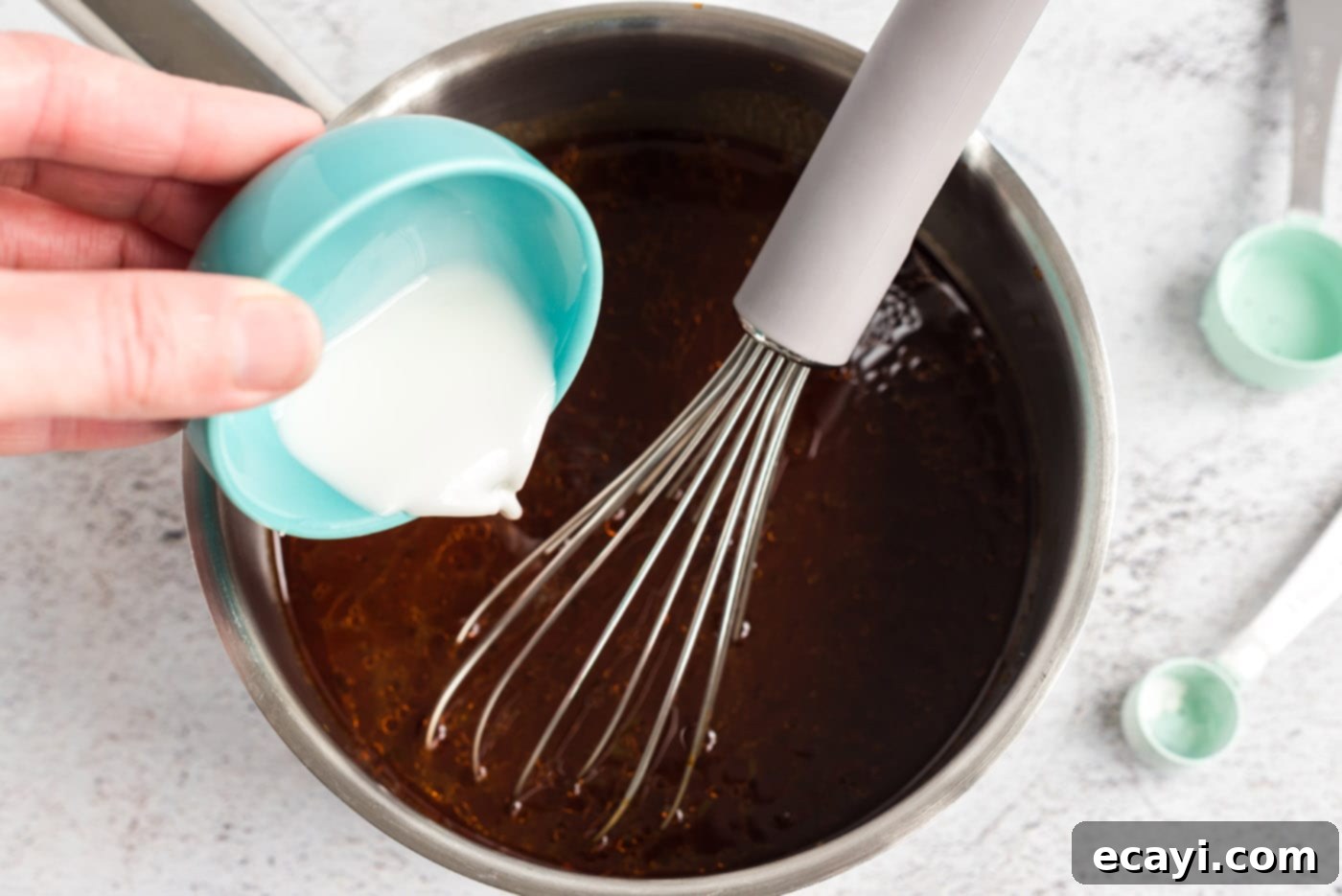 Fall-Apart Tender Slow Cooker Pulled Pork 11 pouring cornstarch into barbecue sauce