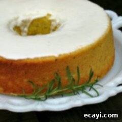 Aromatic Lemon Rosemary Olive Oil Loaf 2 A close up photo of a lemon rosemary olive oil cake resting on a decorative white plate with a rosemary sprig on the side.