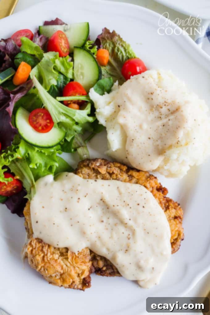 Juicy Chicken Fried Steak smothered in a creamy white gravy, showcasing the perfect texture and delicious flavor. Chicken Fried Steak topped generously with gravy