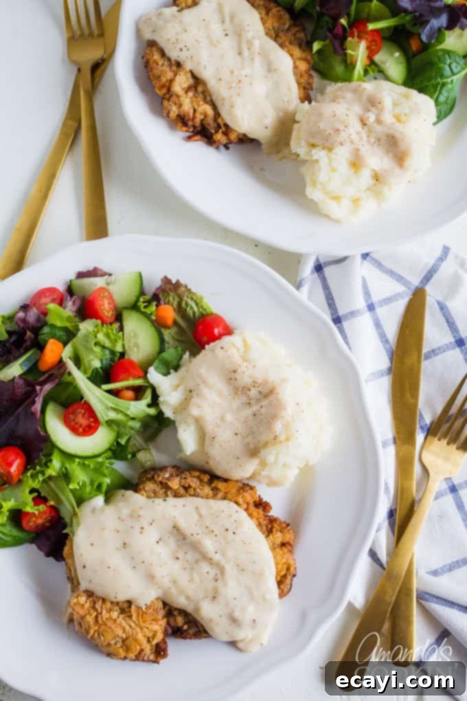 A complete Chicken Fried Steak dinner featuring a crispy steak, creamy mashed potatoes, and a refreshing green salad. Chicken Fried Steak served with mashed potatoes and a side salad