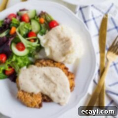 Country Fried Steak 2 chicken fried steak with white gravy and salad on a plate