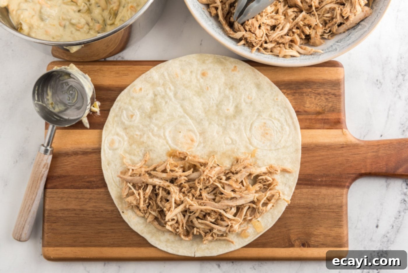 Zesty Chicken Chile Enchiladas 14 Shredded chicken neatly placed on a flour tortilla, ready to be rolled into an enchilada.