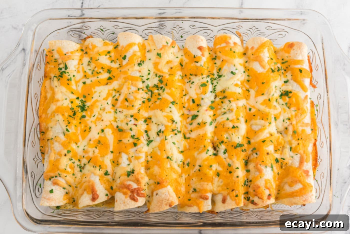 Zesty Chicken Chile Enchiladas 18 Beautifully baked shredded chicken and chile enchiladas fresh out of the oven in a baking dish, with melted, bubbly cheese.