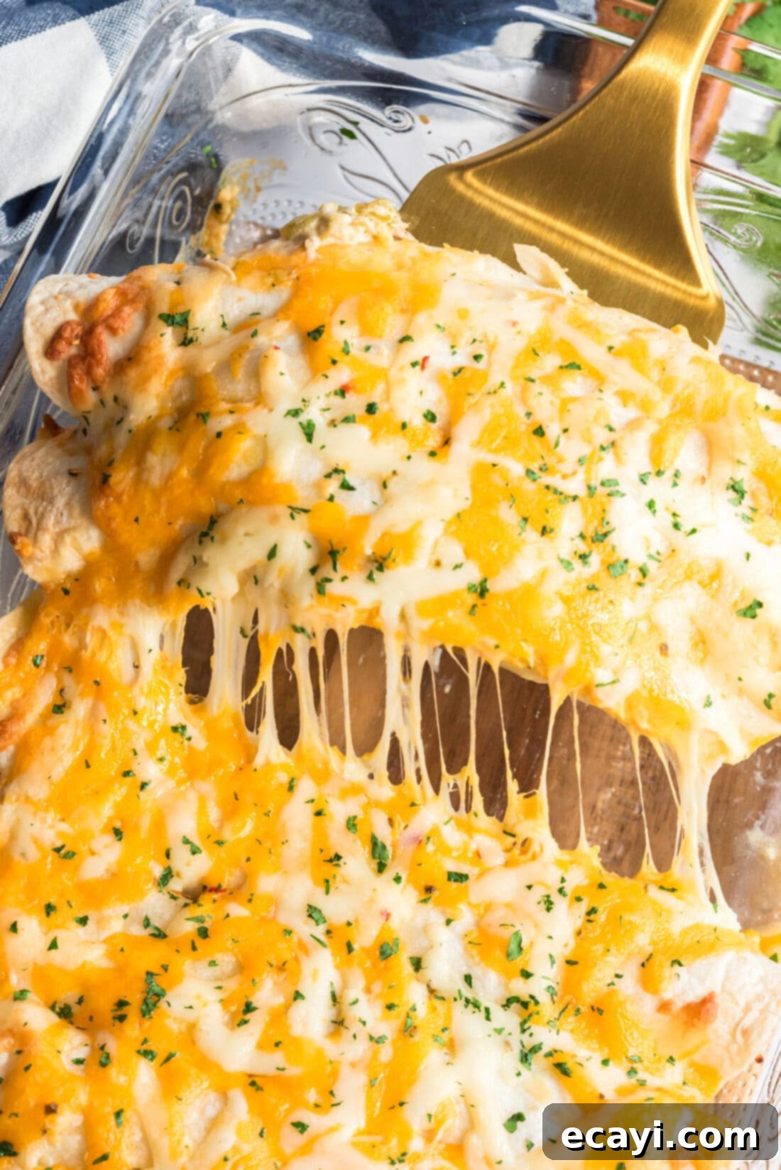 Zesty Chicken Chile Enchiladas 19 A spatula gently lifts two golden-brown shredded chicken and chile enchiladas from the baking pan, showing their perfect texture and melted cheese.