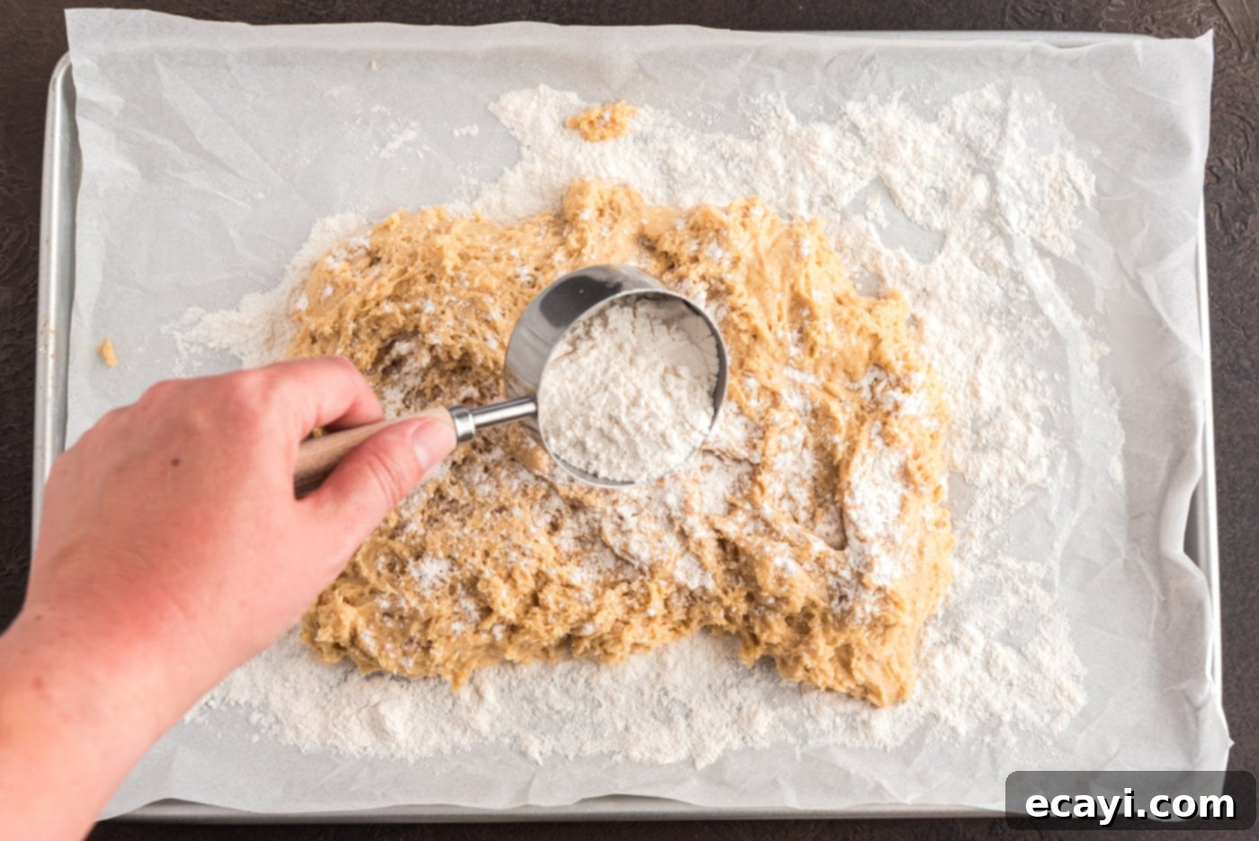 Apple Cider Doughnuts 16 adding flour over doughnut dough on parchment paper to prevent sticking