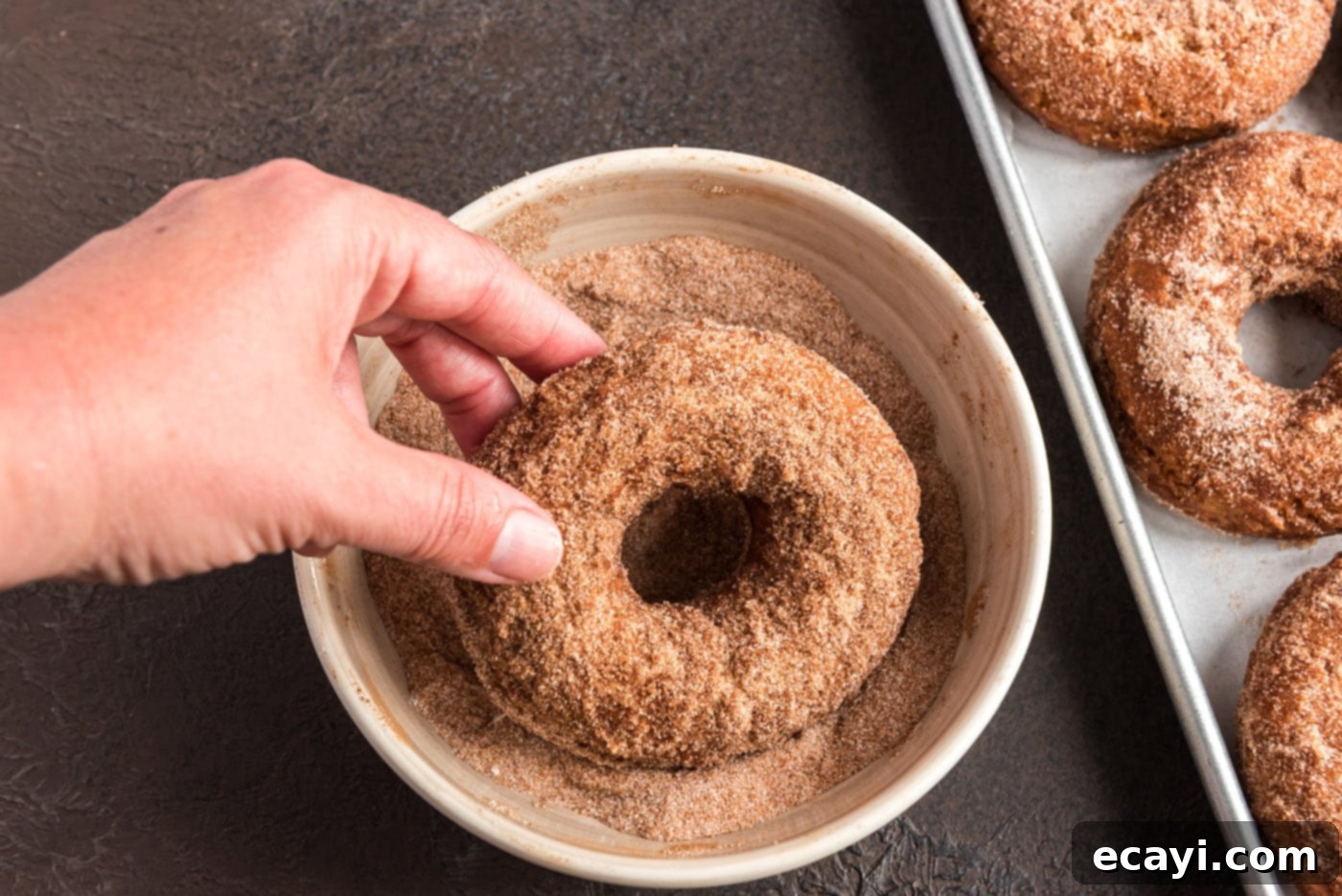 Apple Cider Doughnuts 26 dipping a fried donut into cinnamon sugar mixture