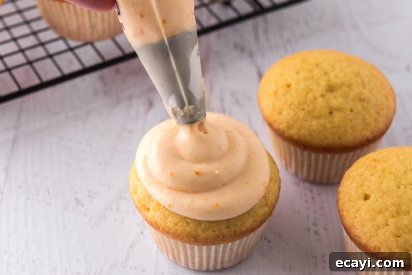 Orange Dream Swirl Cupcakes 13 Piping swirls of orange creamsicle frosting onto baked cupcakes.