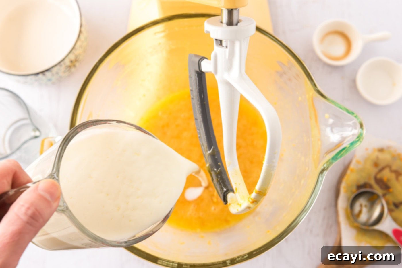 Orange Dream Swirl Cupcakes 6 Buttermilk being poured into the orange-infused egg mixture in a stand mixer.