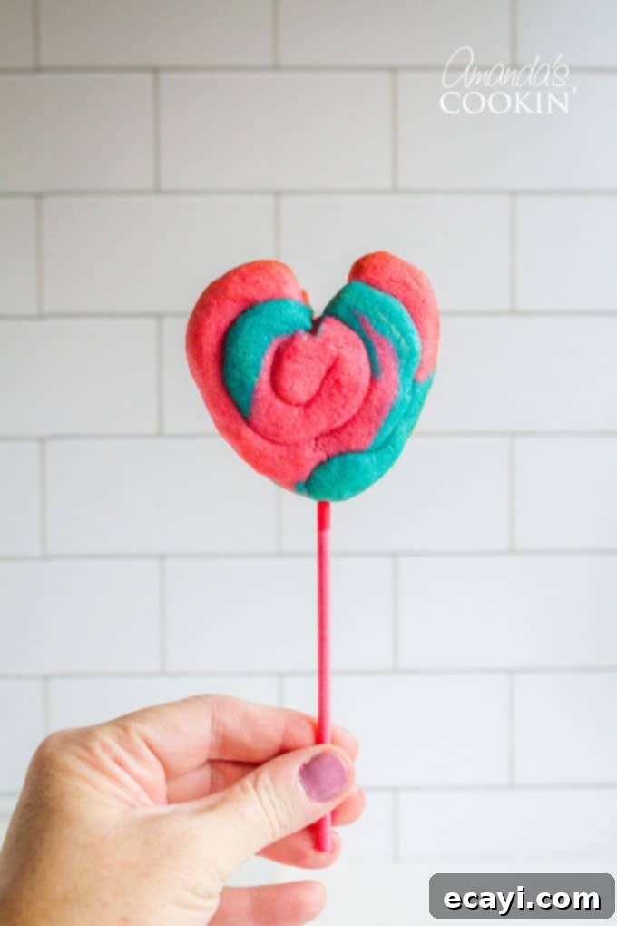 DIY Valentine Play Dough Cookie Pops 5 A hand holding a vibrant Valentine Play Dough Cookie Pop, ready to be enjoyed