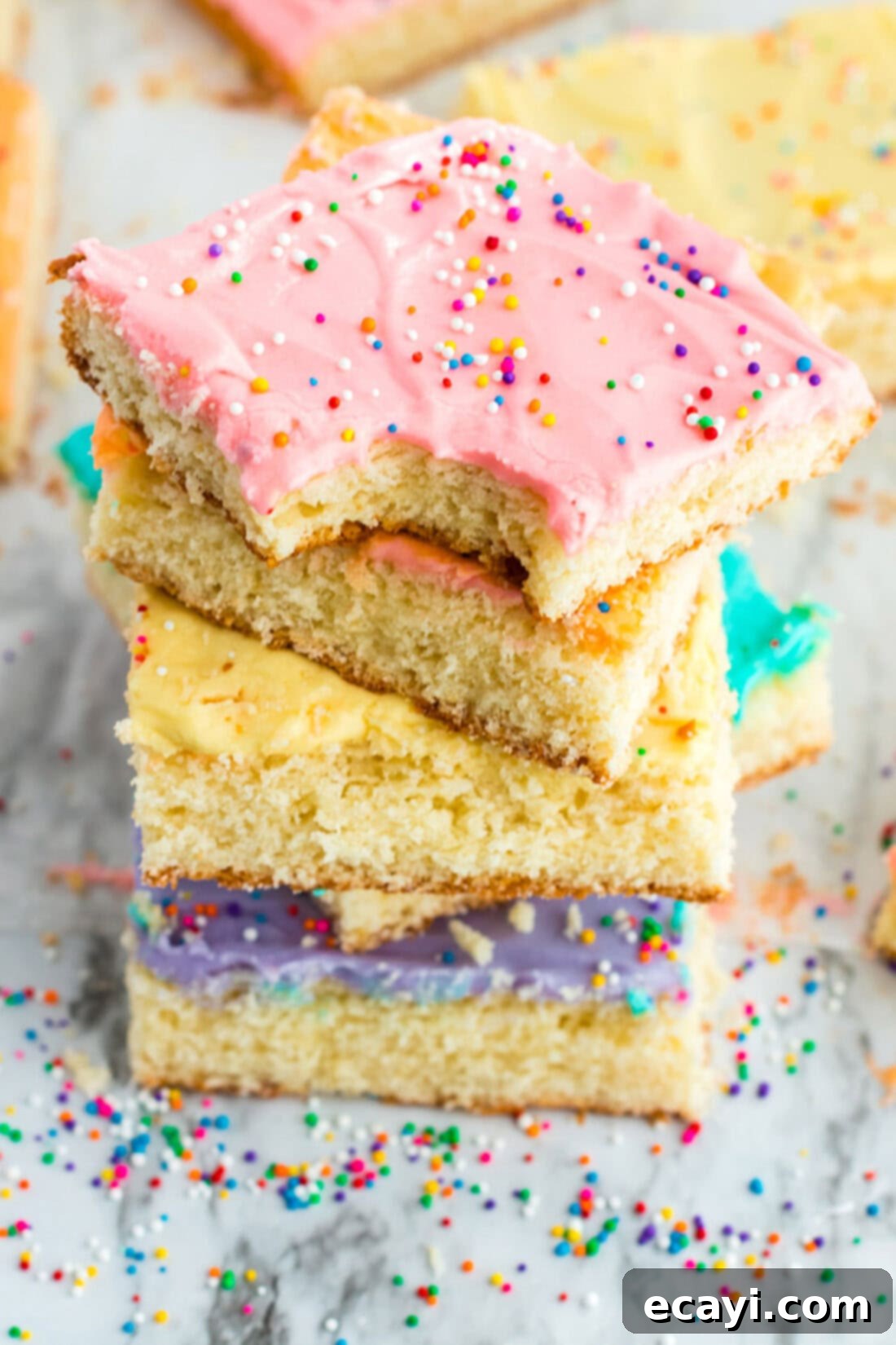 Irresistible Frosted Sugar Cookie Bars 2 Stack of Frosted Sugar Cookie Bars with a bite taken out of the top one, showcasing the soft texture and colorful frosting.