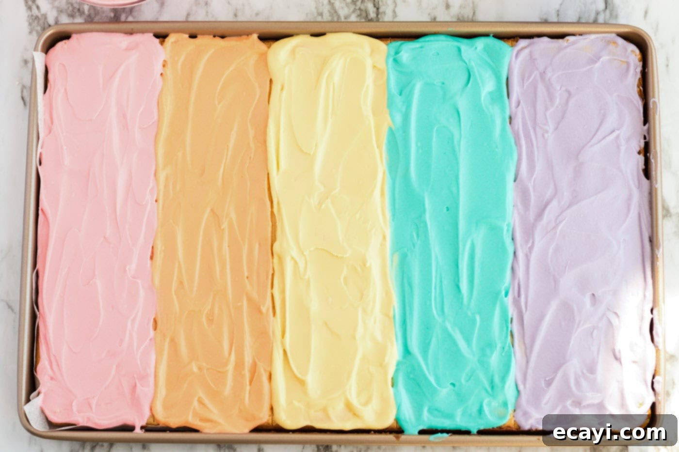 Irresistible Frosted Sugar Cookie Bars 11 A jelly roll pan filled with baked sugar cookie bars, now beautifully frosted in multiple vibrant colors, some already decorated with sprinkles.