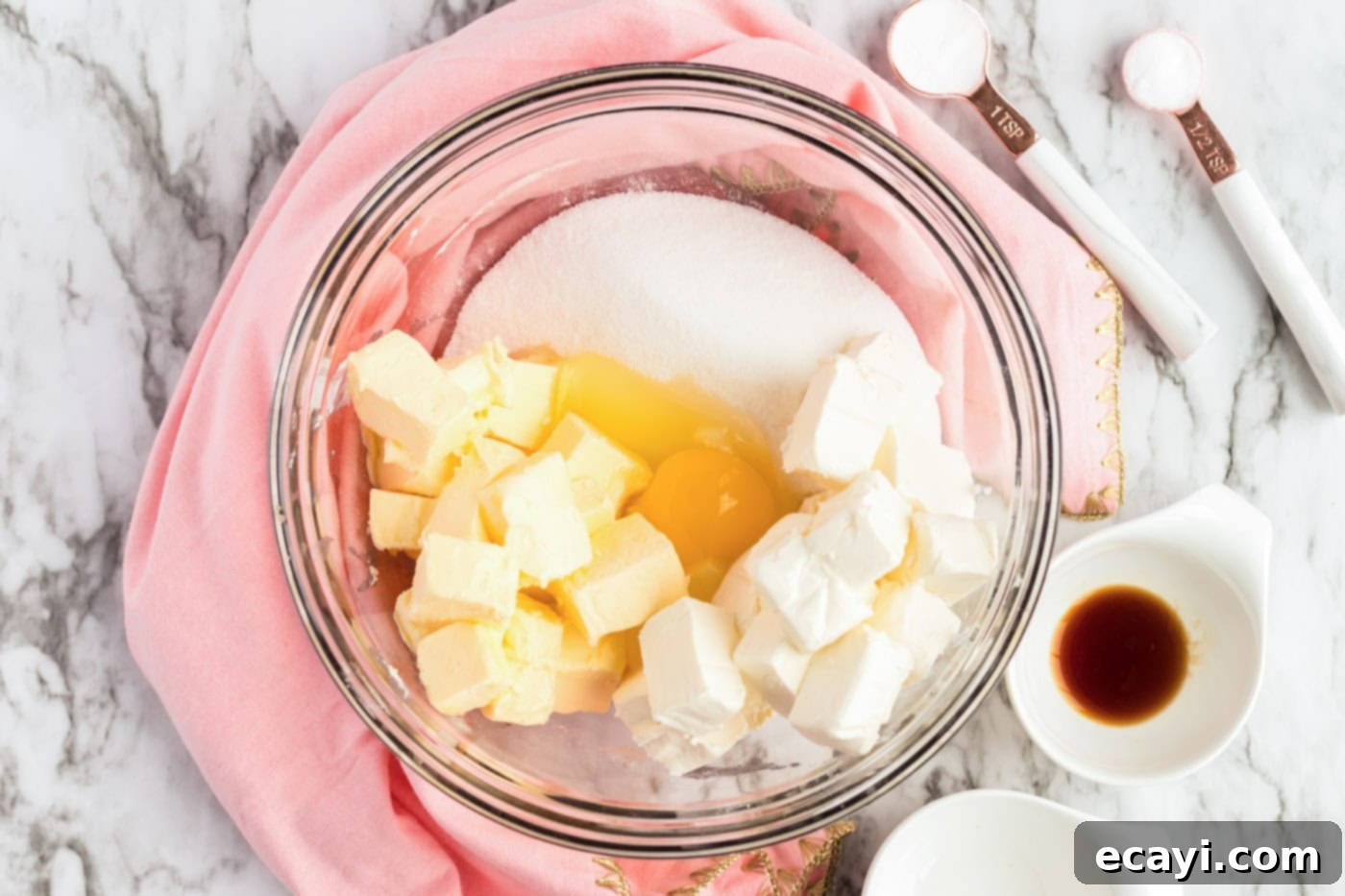 Irresistible Frosted Sugar Cookie Bars 5 Vanilla extract being added to a creamy mixture of butter, cream cheese, sugar, and egg in a mixing bowl.