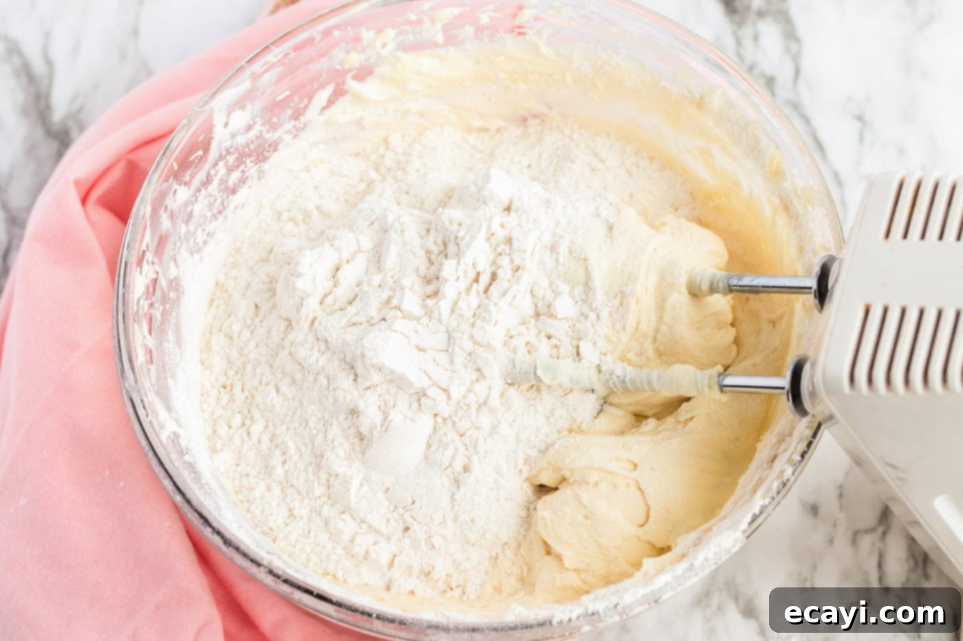 Irresistible Frosted Sugar Cookie Bars 7 All-purpose flour, baking powder, and baking soda being added to the wet butter and sugar mixture in a large mixing bowl.