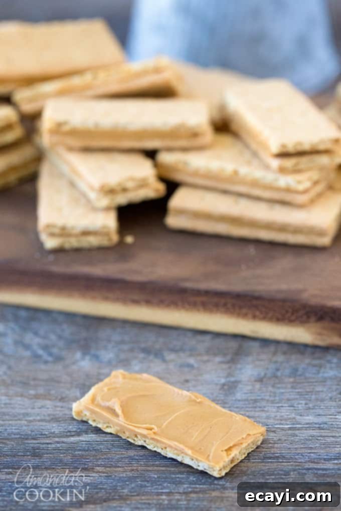 Peanut butter and chocolate lovers and going to go crazy for these super easy to make homemade candy bars. Great for snack or gift giving! #chocolate #candy #desserts #homemade #homemadecandy #candybars #nobake #peanutbutter #valentinesday #peanutbutterdesserts Graham crackers with peanut butter spread on one piece, ready for the top layer