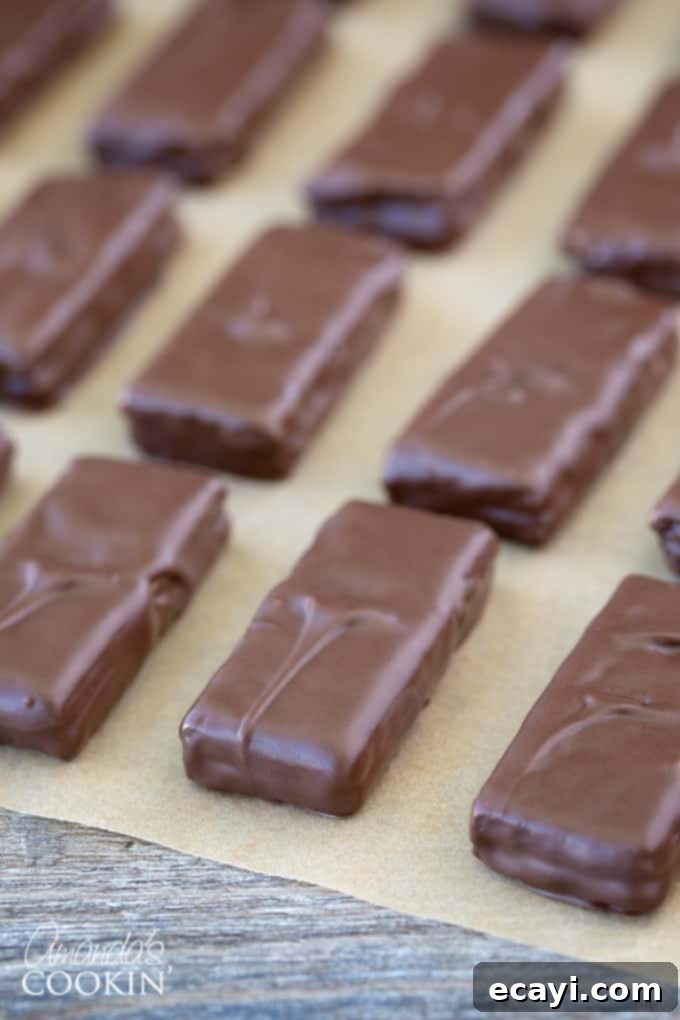 Peanut butter and chocolate lovers and going to go crazy for these super easy to make homemade candy bars. Great for snack or gift giving! #chocolate #candy #desserts #homemade #homemadecandy #candybars #nobake #peanutbutter #valentinesday #peanutbutterdesserts Homemade candy bars being assembled with a generous layer of peanut butter between two graham cracker pieces