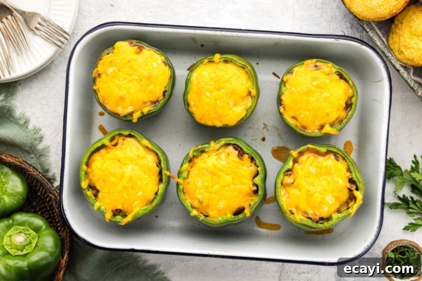 Chili Cornbread Stuffed Peppers 12 Overhead view of perfectly baked chili and cornbread stuffed peppers in a baking dish, with golden-brown cheese and cornbread toppings.