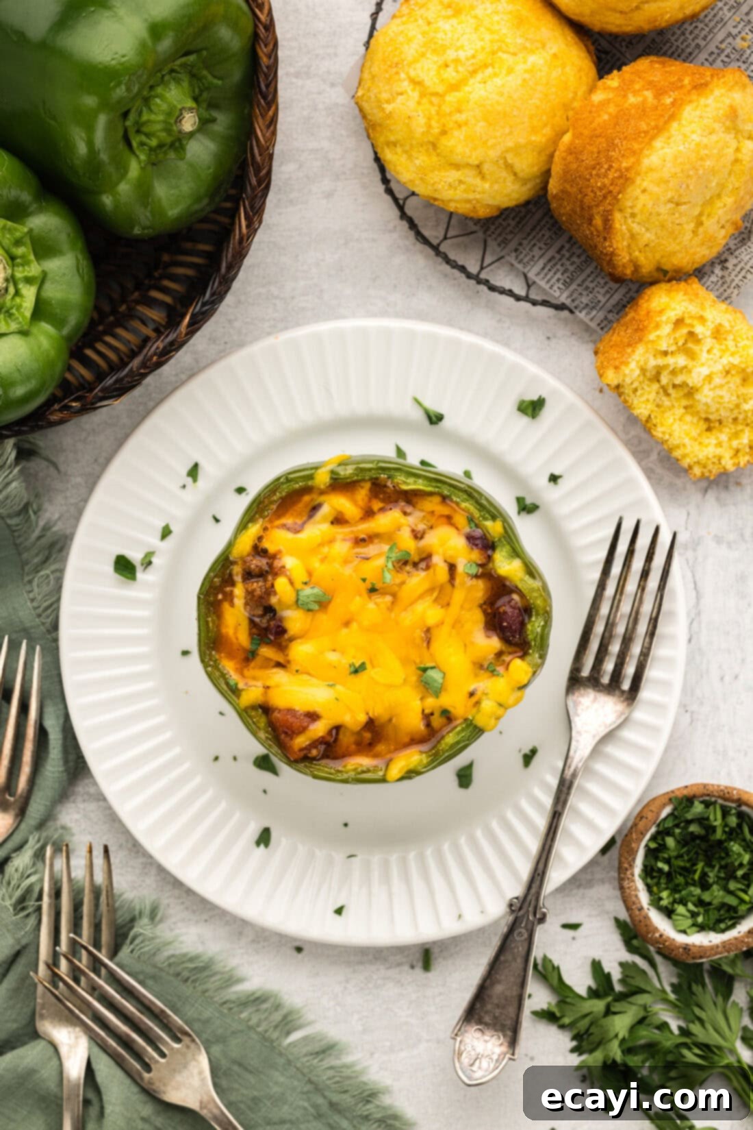 Chili Cornbread Stuffed Peppers 3 Overhead shot of a single chili and cornbread stuffed bell pepper on a white plate, showing the golden cornbread and melted cheese topping.