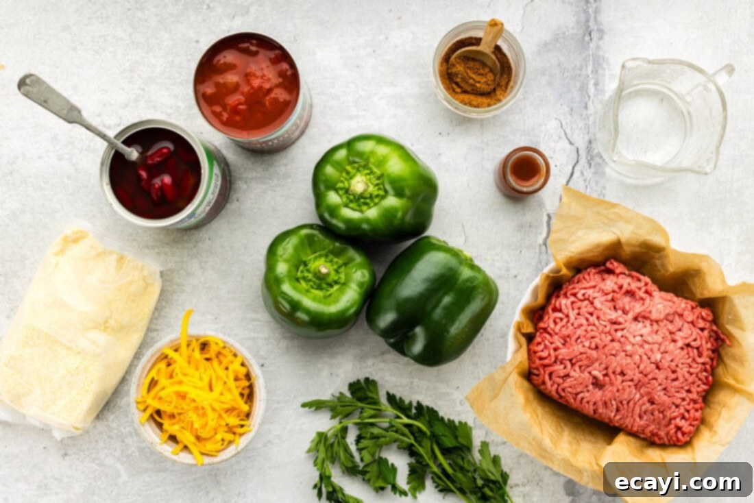 Chili Cornbread Stuffed Peppers 4 A flat lay photograph showcasing all the fresh ingredients needed for chili and cornbread stuffed peppers, including bell peppers, ground beef, chili seasoning, beans, tomatoes, cornbread mix, and shredded cheese.