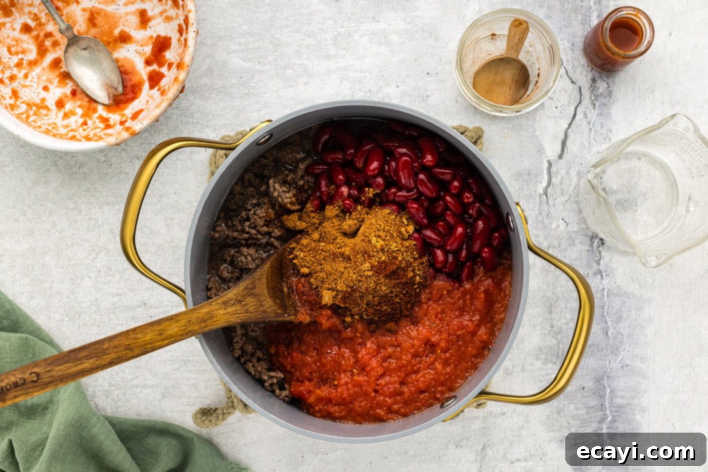 Chili Cornbread Stuffed Peppers 6 Ground beef cooking in a pot, with chili seasoning, diced tomatoes, and kidney beans being added to create a rich chili base.