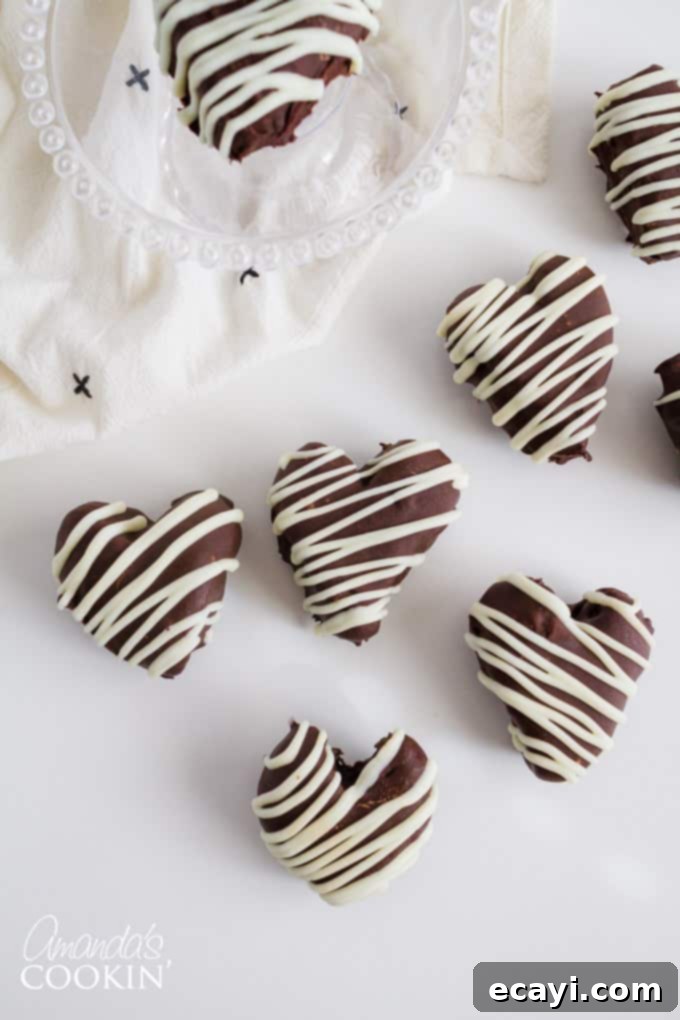 These Heart Oreo Truffles make a great Valentine's Day treat! Suprise your sweetheart with these or bring them to the office for everyone to enjoy! #oreoballs #oreo #oreodessert #desserts #truffles #valentinesday #valentinesdaydessert #nobake #chocolate Heart Oreo Truffles with white chocolate drizzle, presented beautifully on a platter for Valentine's Day