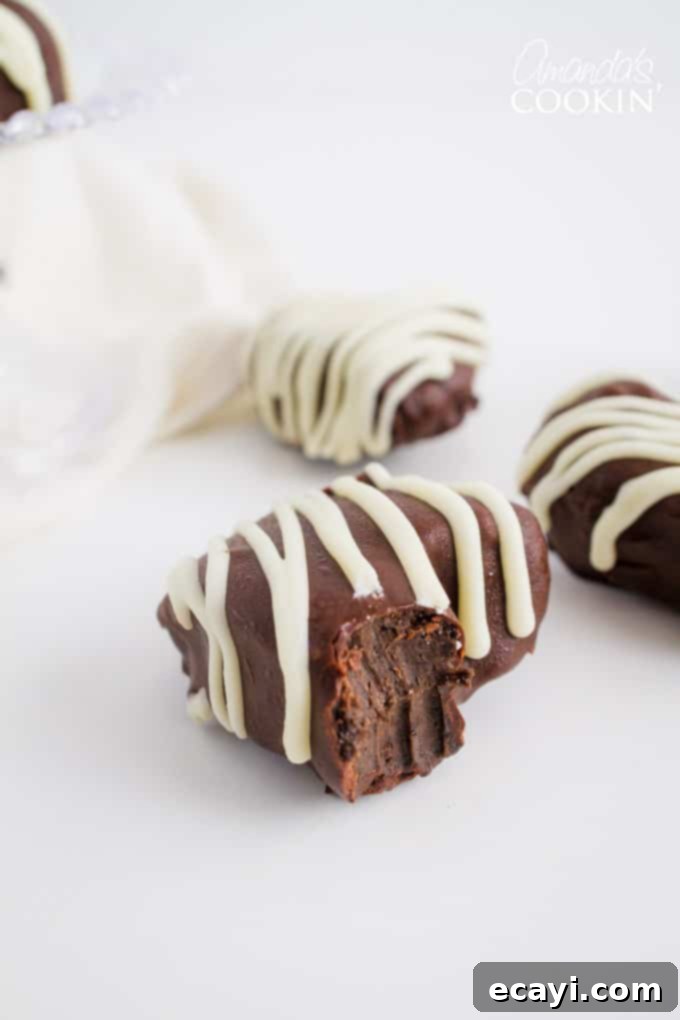 These Heart Oreo Truffles make a great Valentine's Day treat! Suprise your sweetheart with these or bring them to the office for everyone to enjoy! #oreoballs #oreo #oreodessert #desserts #truffles #valentinesday #valentinesdaydessert #nobake #chocolate Heart Oreo Truffle with a small bite taken out, revealing its creamy interior