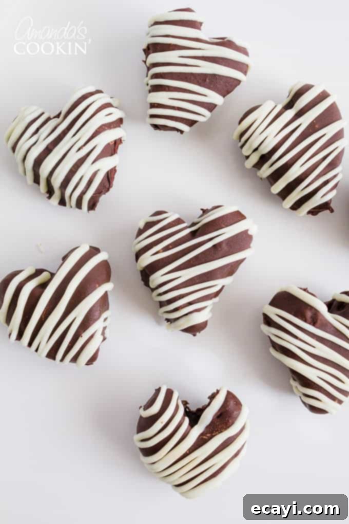 These Heart Oreo Truffles make a great Valentine's Day treat! Suprise your sweetheart with these or bring them to the office for everyone to enjoy! #oreoballs #oreo #oreodessert #desserts #truffles #valentinesday #valentinesdaydessert #nobake #chocolate Seven beautifully arranged Heart Oreo Truffles, each with a delicate white chocolate drizzle