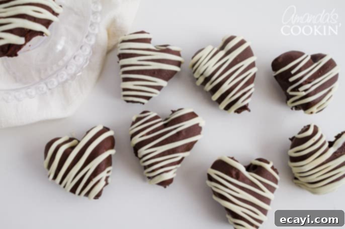 These Heart Oreo Truffles make a great Valentine's Day treat! Suprise your sweetheart with these or bring them to the office for everyone to enjoy! #oreoballs #oreo #oreodessert #desserts #truffles #valentinesday #valentinesdaydessert #nobake #chocolate Assortment of Heart Oreo Truffles on a white background, ready for Valentine's Day