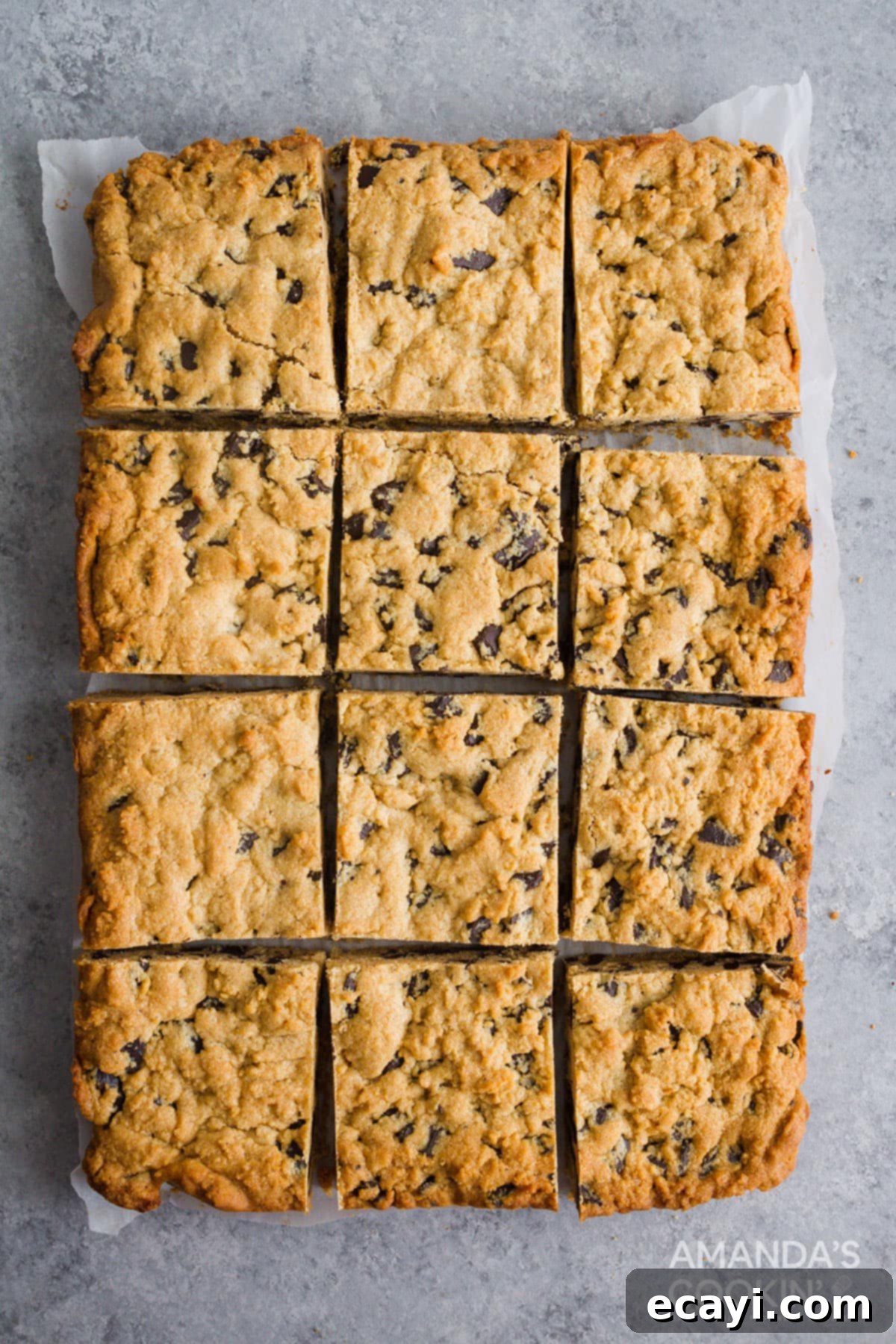 Ultimate Peanut Butter Chocolate Chip Bars 3 Close-up overhead view of golden brown peanut butter chocolate chunk bars arranged neatly on parchment paper, showcasing their rich texture and abundant chocolate pieces.