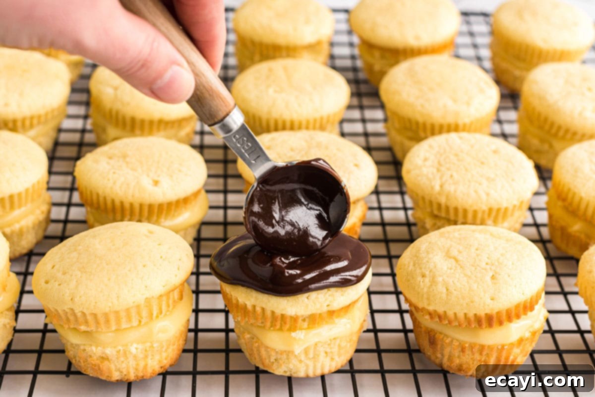Spreading Ganache on Cupcake Spreading chocolate ganache evenly over the top of a Boston Cream Cupcake with a spoon