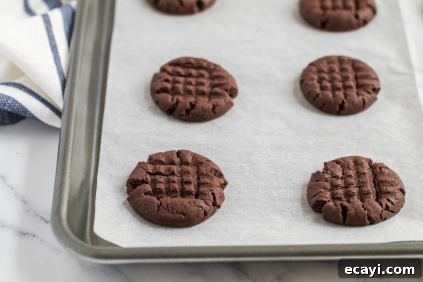 The Ultimate Chocolate Peanut Butter Cookies 9 Freshly baked chocolate peanut butter cookies, golden brown and perfectly set, on a parchment-lined baking sheet.