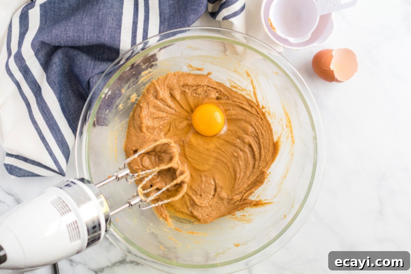 The Ultimate Chocolate Peanut Butter Cookies 5 A single egg being added to the thoroughly creamed shortening, peanut butter, brown sugar, milk, and vanilla mixture.