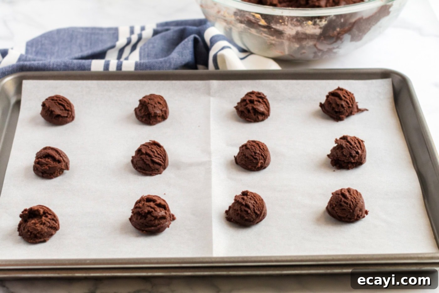 The Ultimate Chocolate Peanut Butter Cookies 7 Portioned chocolate peanut butter cookie dough balls neatly arranged on a parchment-lined baking sheet, ready for the oven.