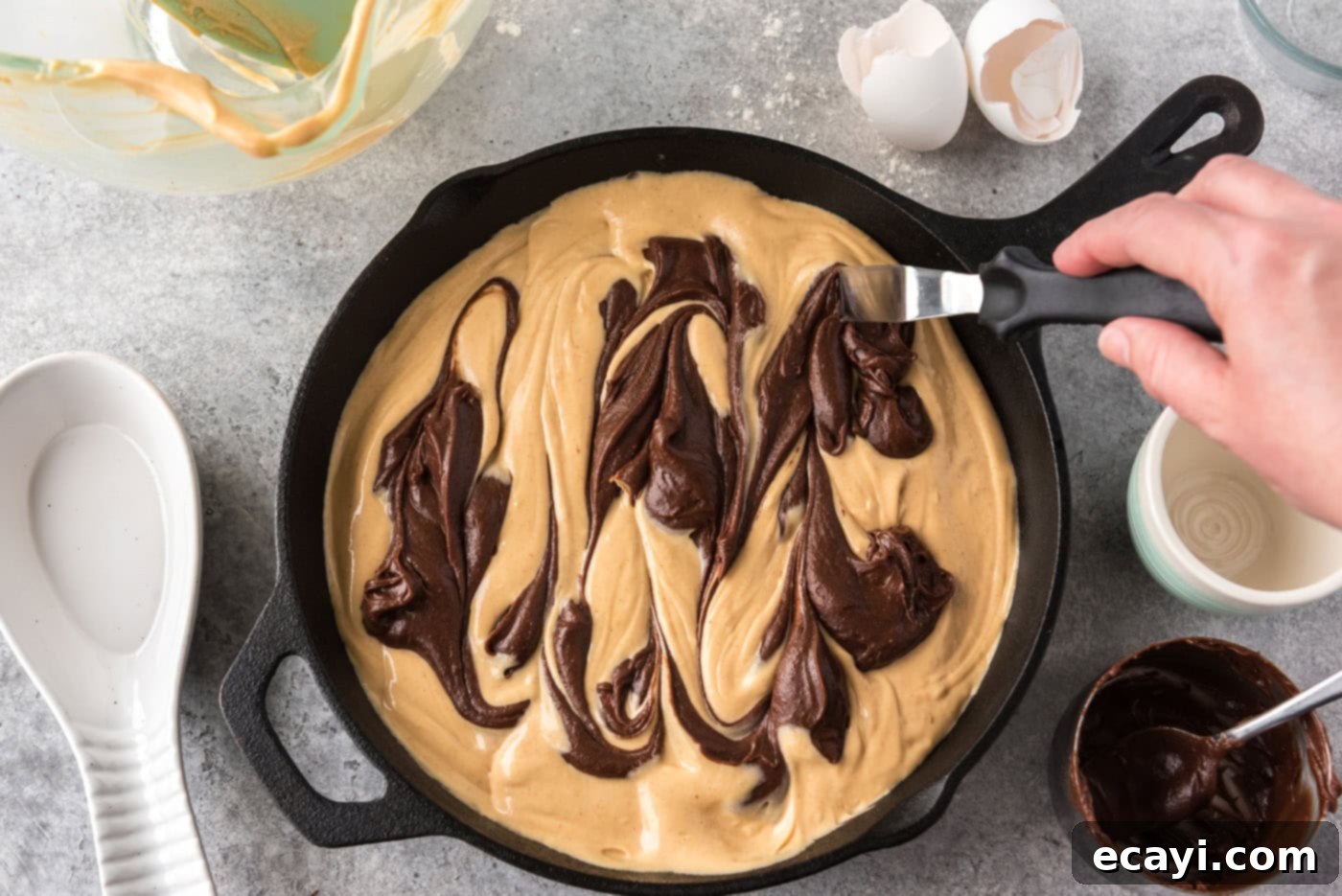 Deep Dish Peanut Butter Brownie 14 hand using an icing spatula to create swirls of brownie batter on top of peanut butter mixture