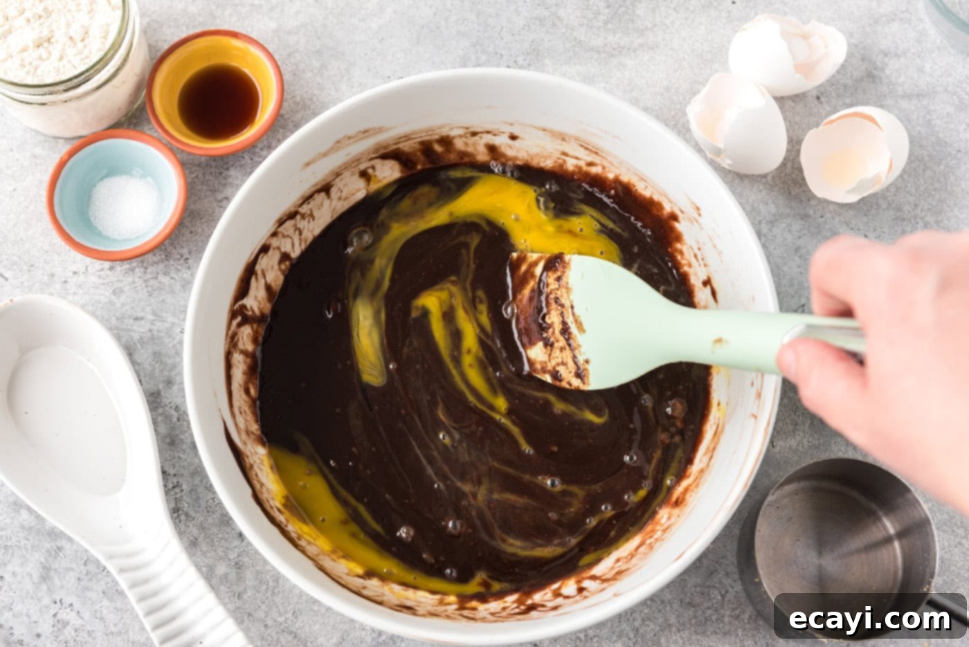Deep Dish Peanut Butter Brownie 9 rubber spatula stirring egg into brownie batter in a bowl