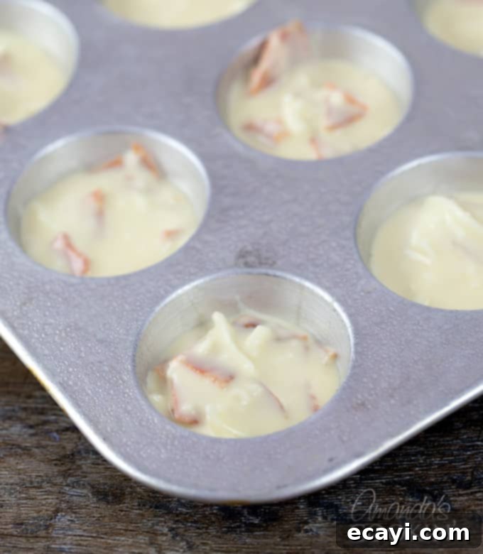 Cheesy Pepperoni Pizza Bites 7 A mini muffin tray filled with uncooked pizza puff batter, ready for baking.